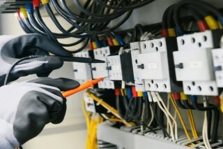 Technicien contrôlant un tableau électrique avec un multimètre